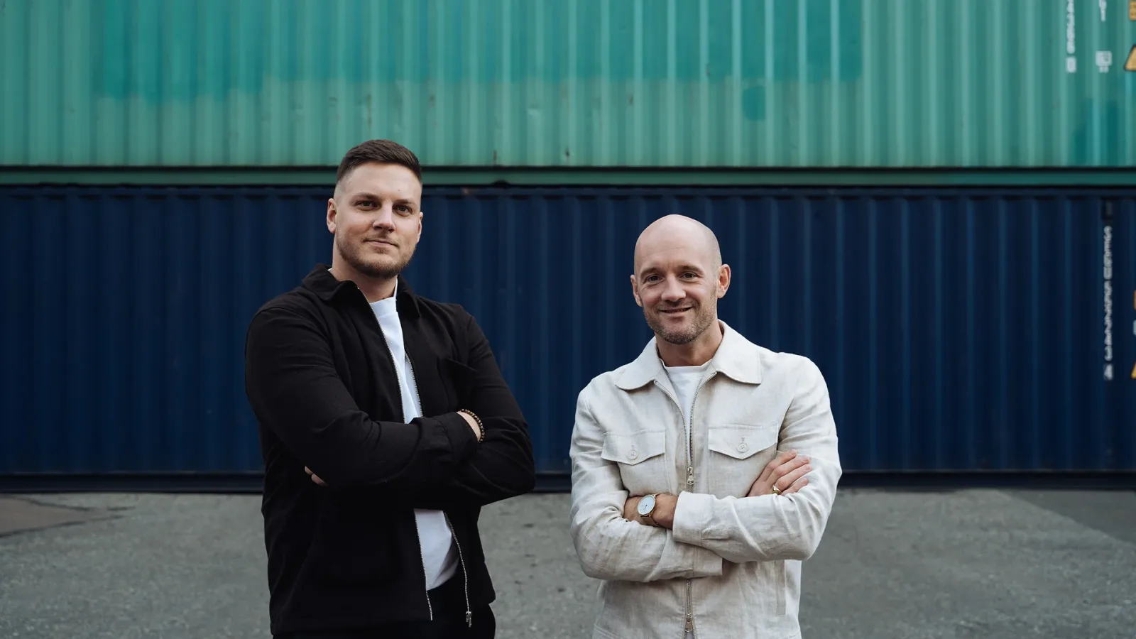 Two Tullify customs experts in front of a wall of containers