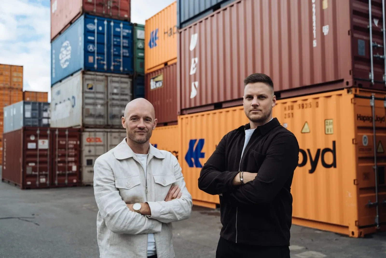 Two Tullify customs experts in front of stacked containers