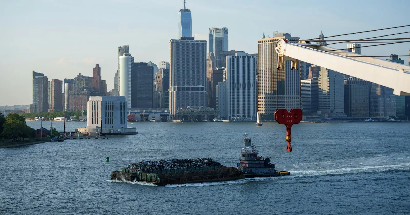 Lower Manhattan seen from Brooklyn, with a barge and a crane in the foreground