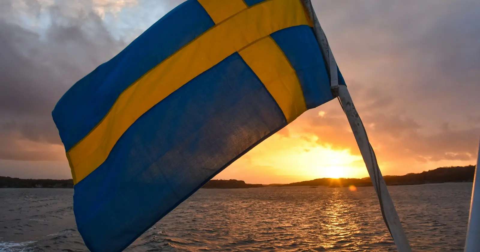 The Swedish flag at the stern of a boat at sunset