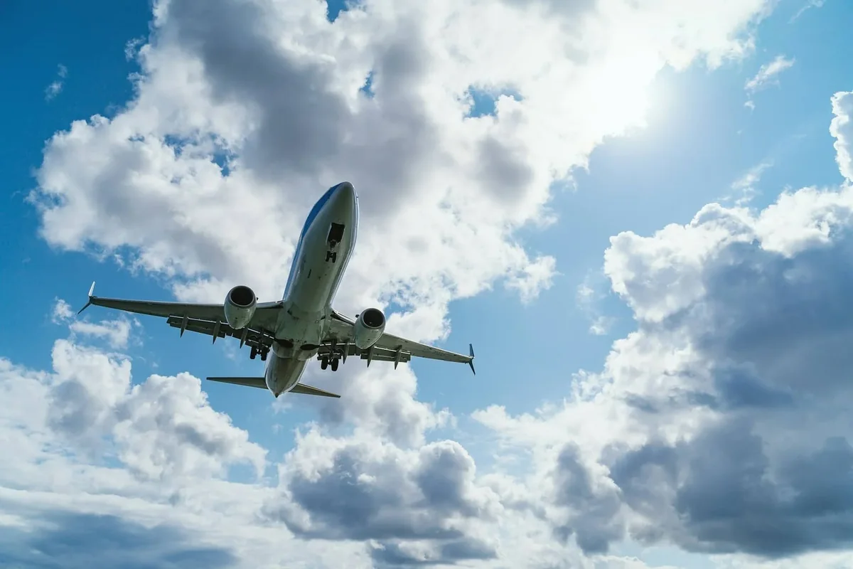 Passasjerfly på vei inn for landing mot en skyet himmel