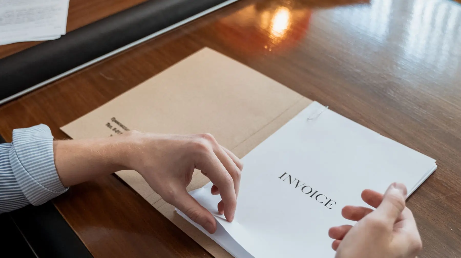 En handelsfaktura överst i en bunt underlag på ett skrivbord