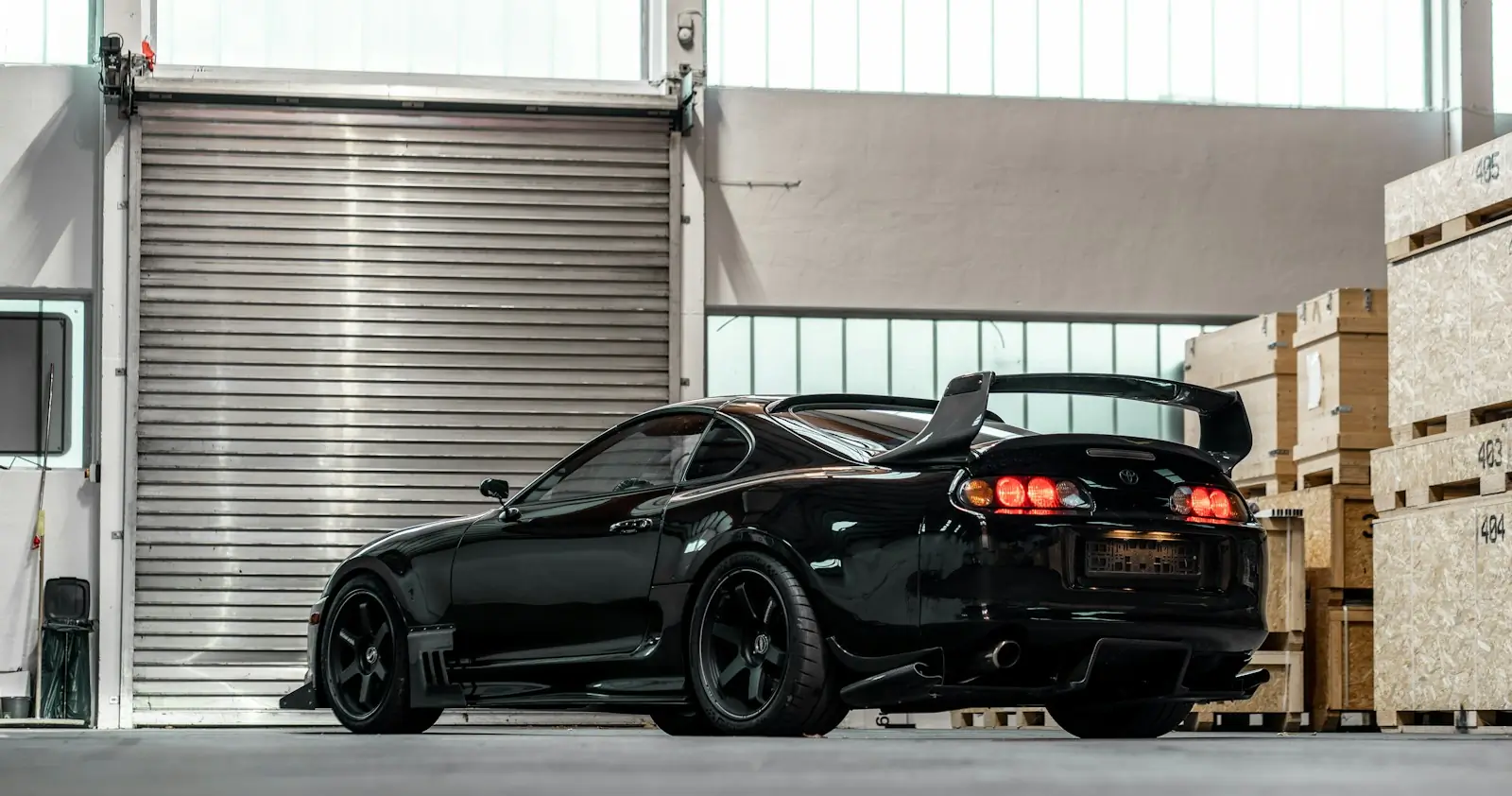 En svart Toyota Supra parkert foran en rulleport