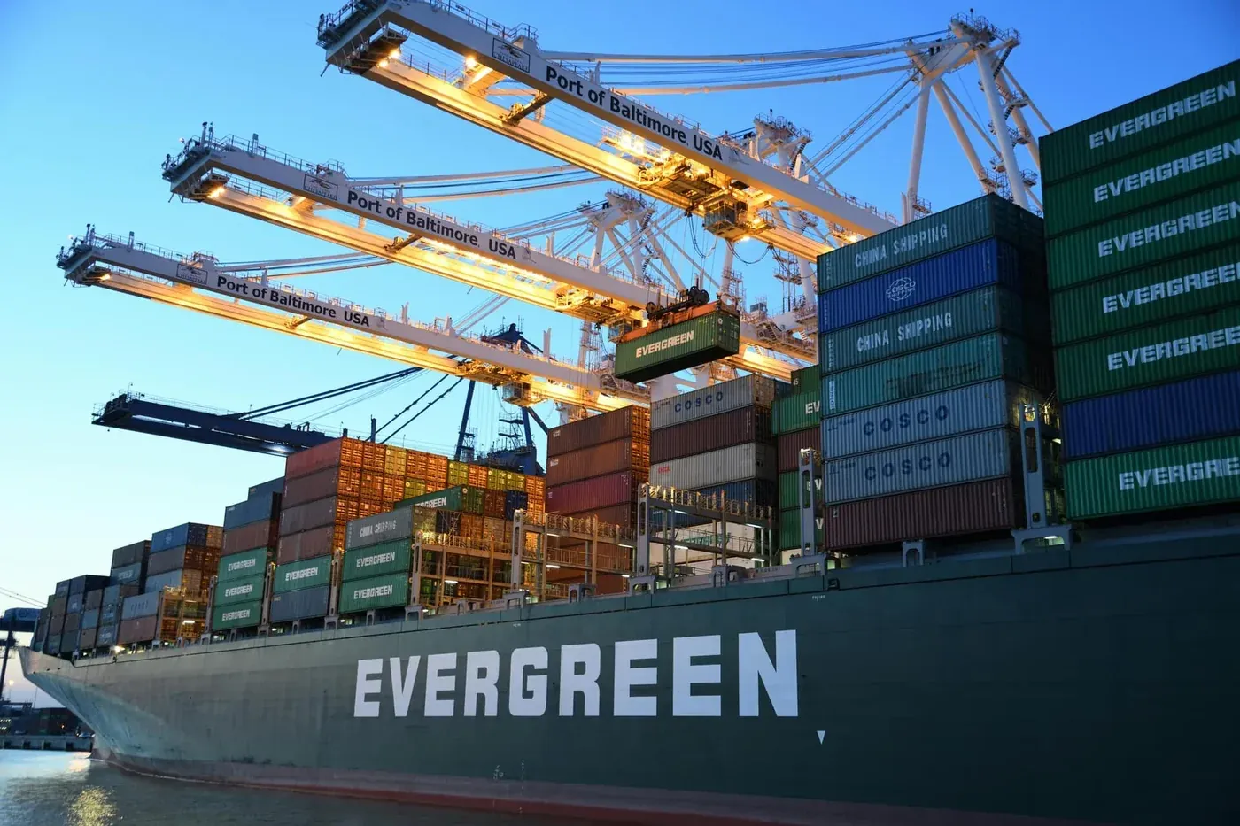 Portalkraner som laster containere på et skip i skumring