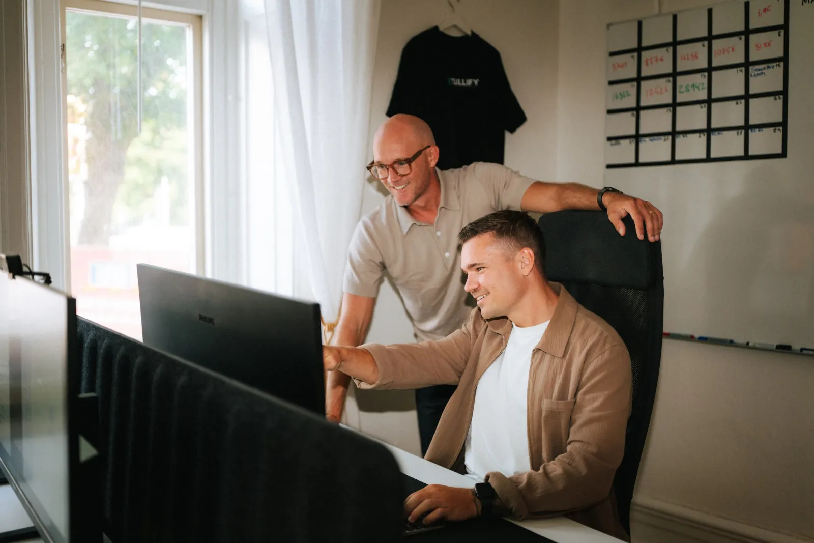 Richard Coster och David Olsson tittar på en skärm vid ett skrivbord på Tullifys kontor
